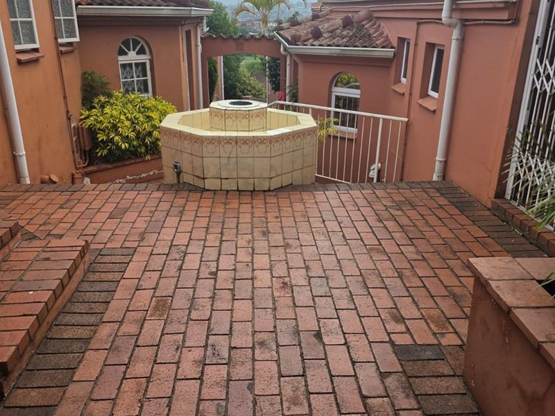 Rear courtyard area featuring brick paving, a central tiled fountain, and surrounding townhouse architecture with terracotta roof tiles.