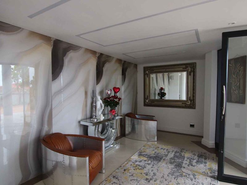 A modern entrance hall featuring striking large-format marble-effect wall cladding, recessed ceiling lighting, and a sleek glass-panelled door.