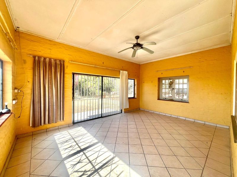 Spacious living area featuring tiled flooring, a ceiling fan, and large sliding doors leading to the exterior, providing ample natural light.