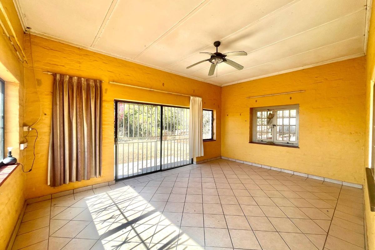 Spacious living area featuring tiled flooring, a ceiling fan, and large sliding doors leading to the exterior, providing ample natural light.