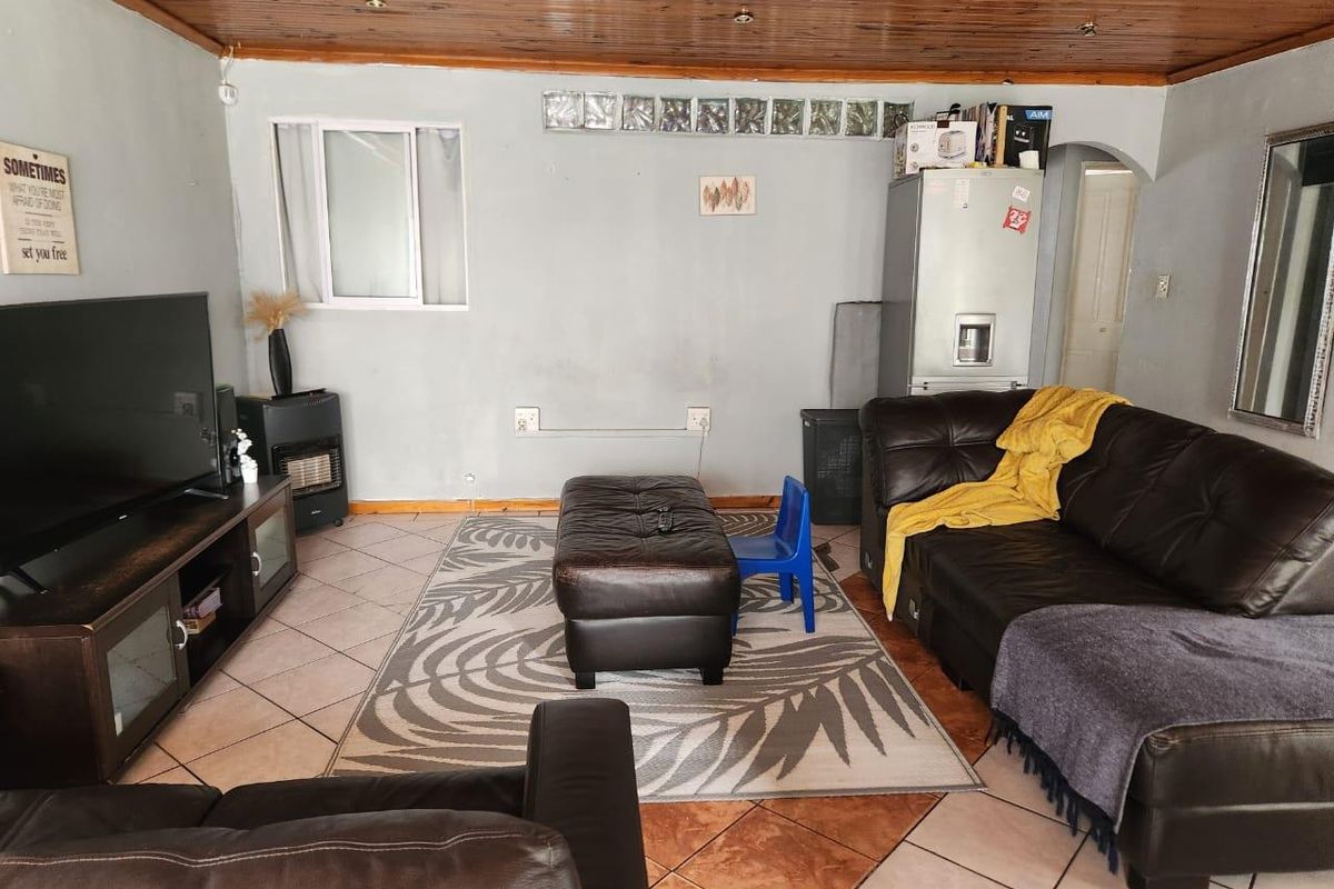 A living room featuring a timber ceiling, tiled flooring, and a glass block window, offering a functional space with potential for cosmetic updates.