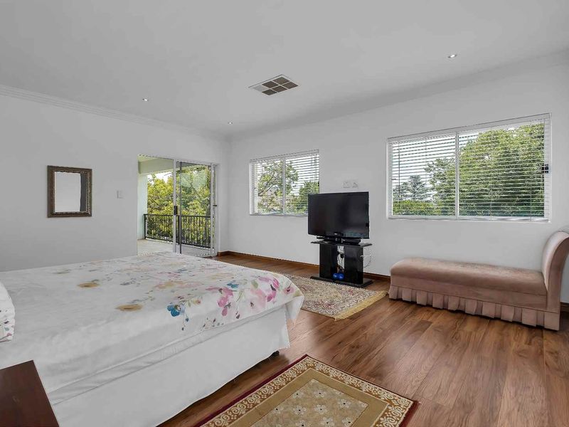 Spacious bedroom featuring laminate flooring, recessed downlights, and a sliding glass door providing access to an outdoor balcony area.