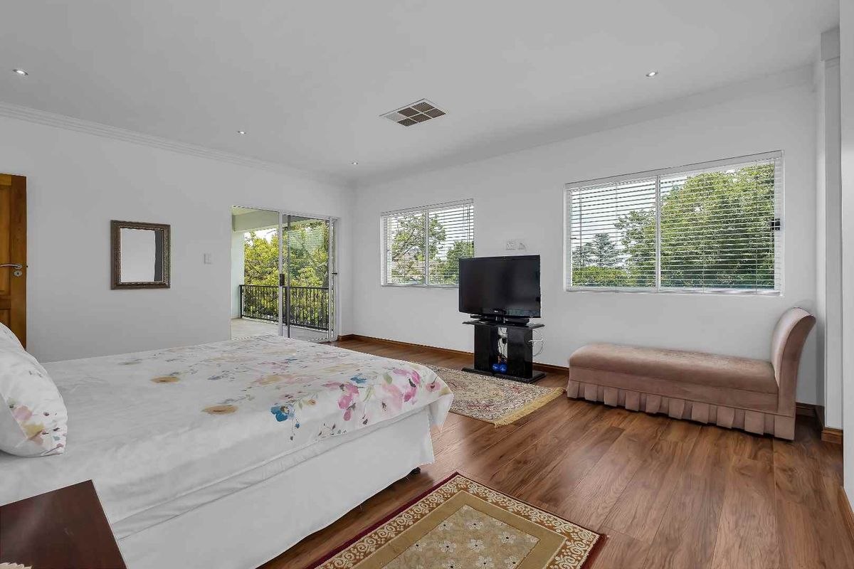 Spacious bedroom featuring laminate flooring, recessed downlights, and a sliding glass door providing access to an outdoor balcony area.
