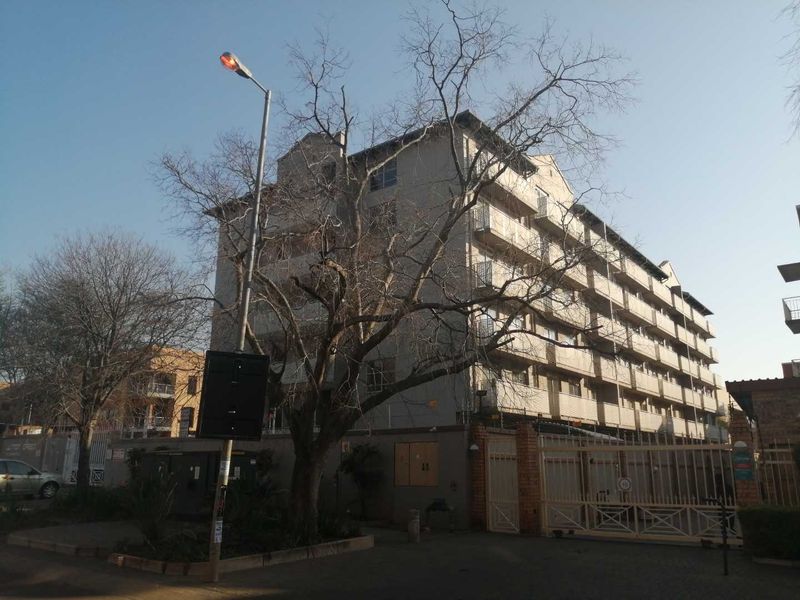 Exterior view of a multi-story apartment building featuring private balconies and a secure gated entrance.