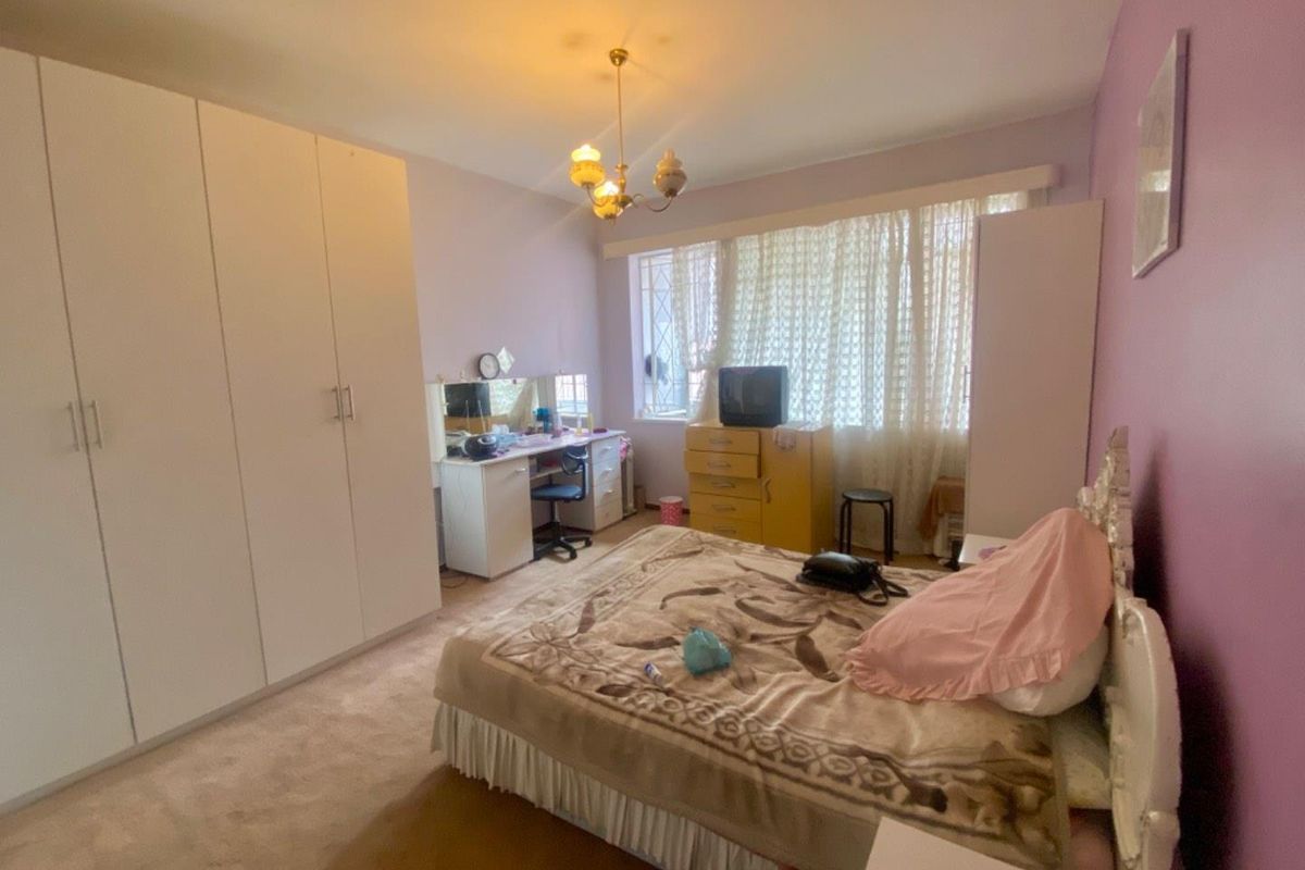 A spacious bedroom featuring built-in floor-to-ceiling wardrobes, neutral carpeting, and large windows that provide ample natural light.