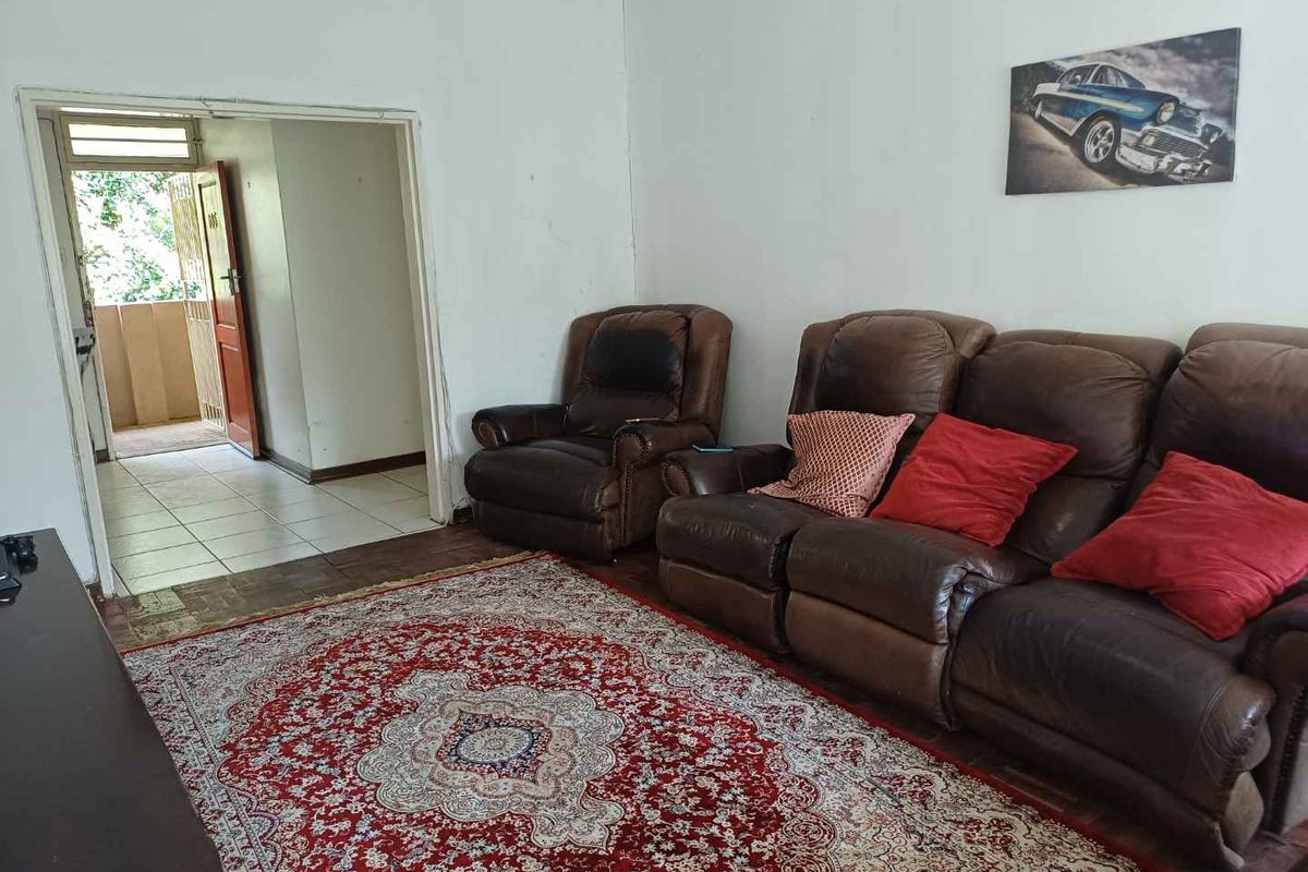 A living room area featuring tiled flooring and access to an adjacent balcony through a doorway.