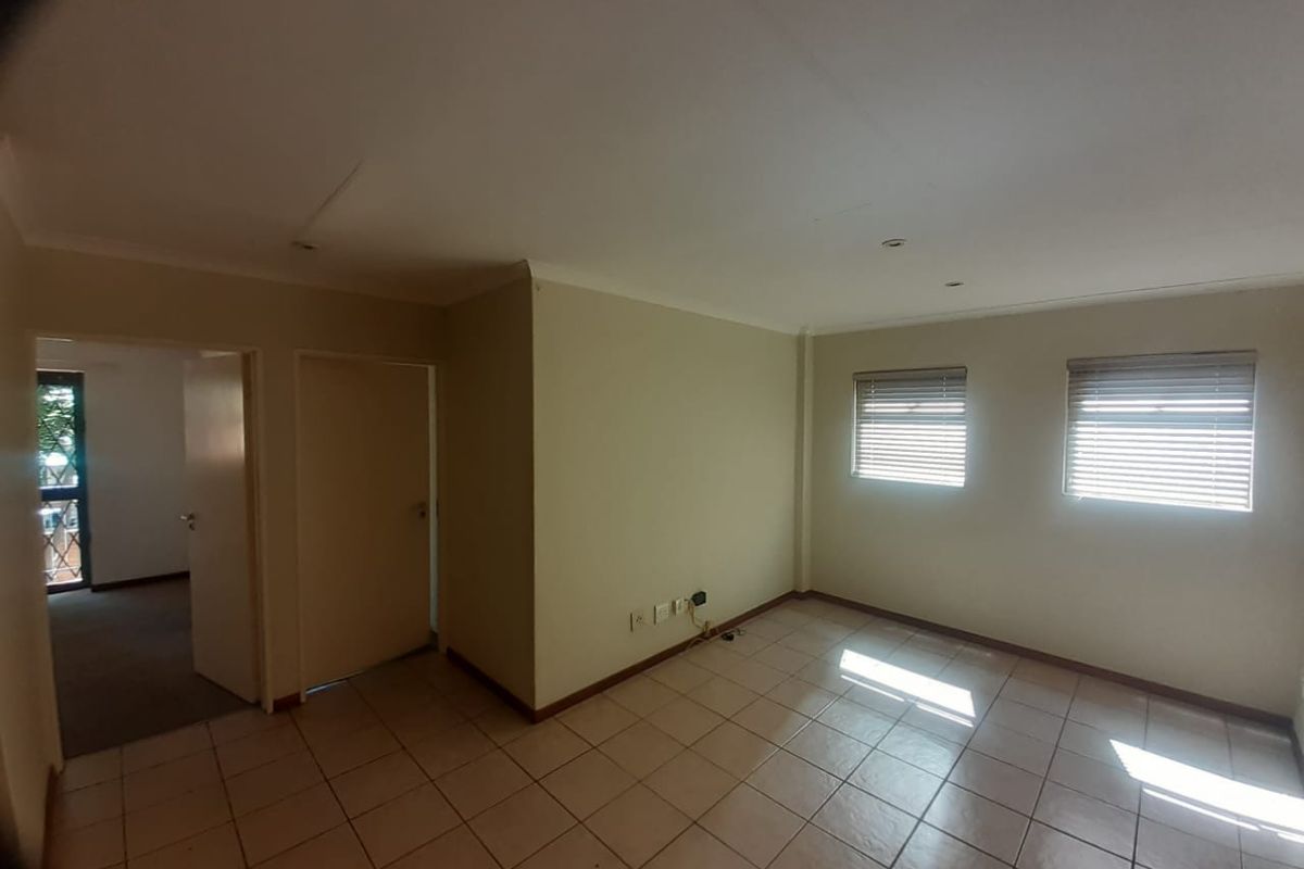 An empty living room featuring tiled flooring, recessed downlights, and venetian blinds, offering a neutral blank canvas for potential interior design updates.