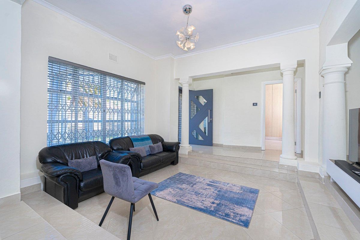 Spacious living area featuring tiled flooring, decorative columns, and a modern entrance door, creating an open and inviting atmosphere.