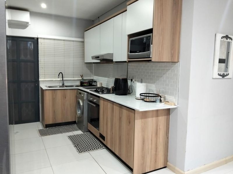 Modern kitchen featuring wood-grain cabinetry, subway tile backsplash, integrated appliances, and a sleek countertop, providing a functional and contemporary cooking space.