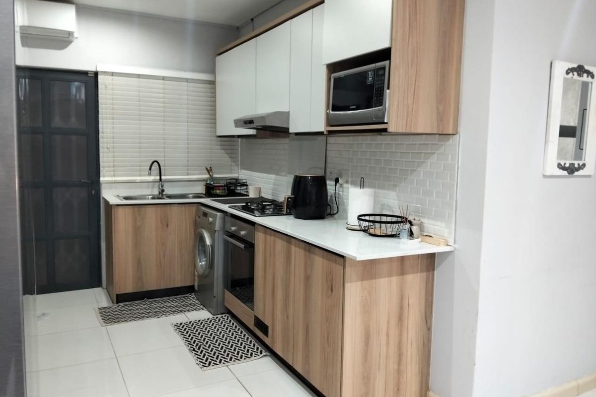 Modern kitchen featuring wood-grain cabinetry, subway tile backsplash, integrated appliances, and a sleek countertop, providing a functional and contemporary cooking space.