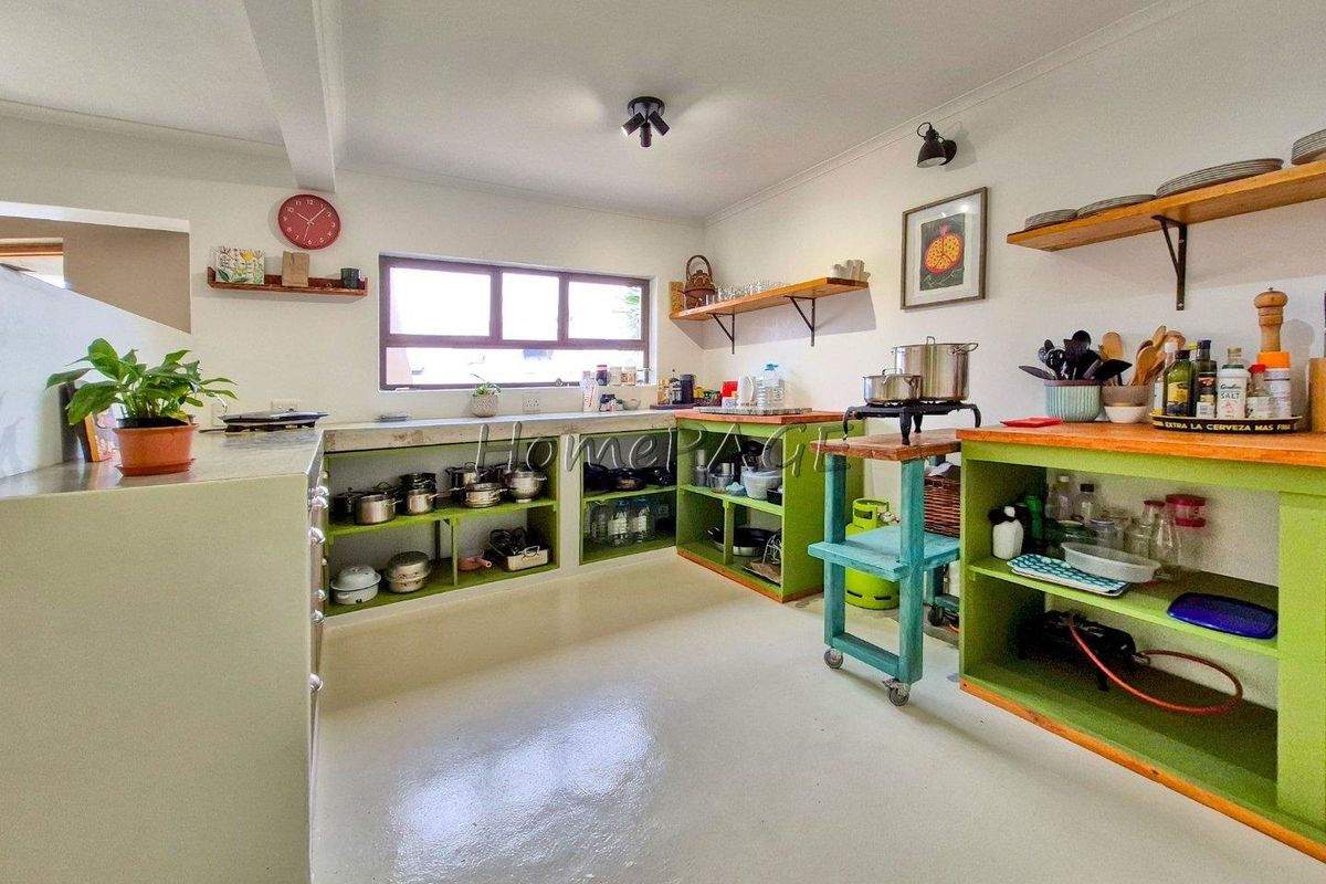 A rustic kitchen featuring open shelving, concrete countertops, and a functional layout with ample storage space for culinary essentials.