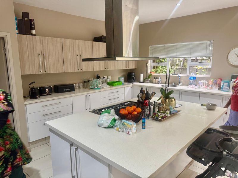 Modern kitchen featuring a large central island with quartz countertops, gas hob, stainless steel extractor fan, and ample built-in cabinetry.