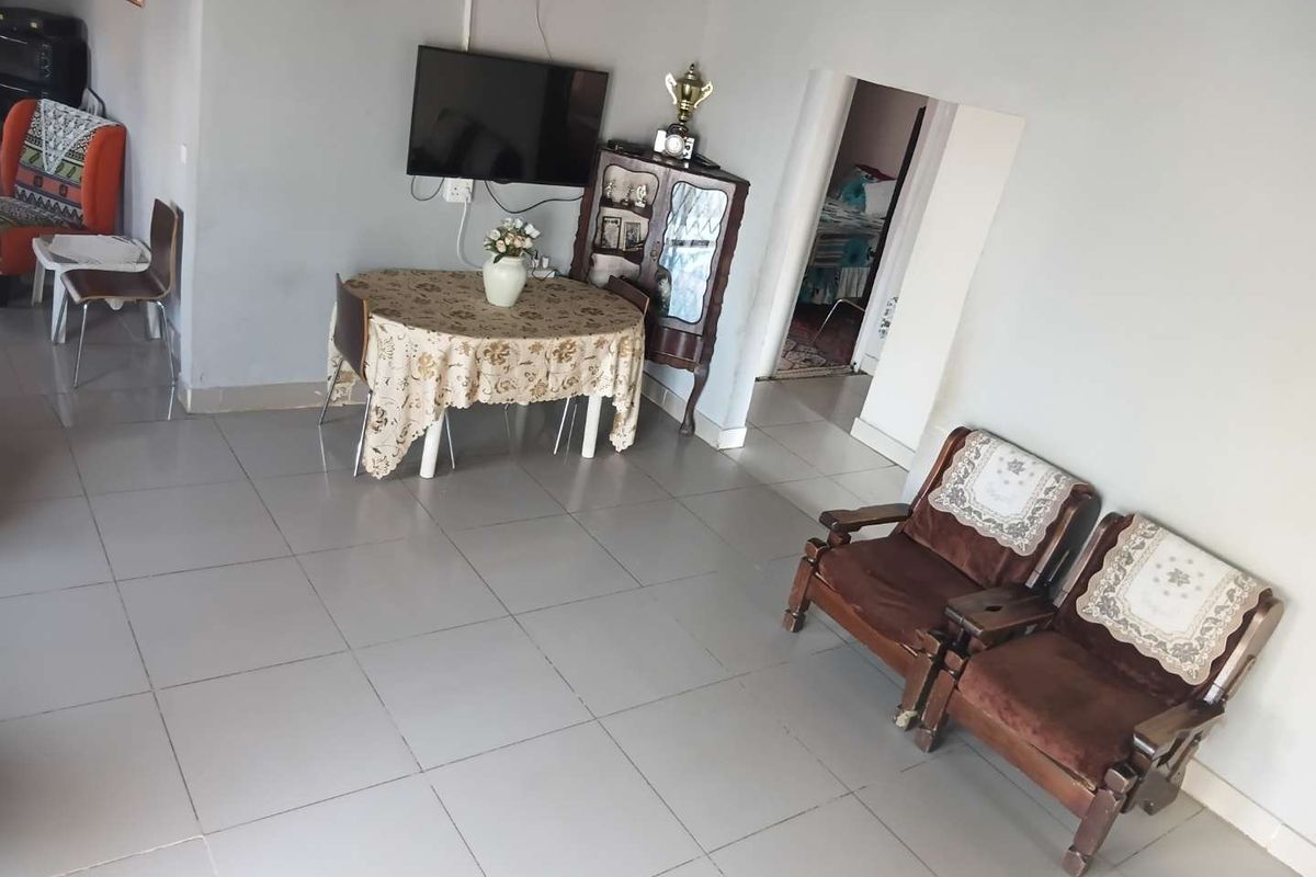 A living area featuring neutral tiled flooring and plain walls, providing a functional space with potential for modern updates.