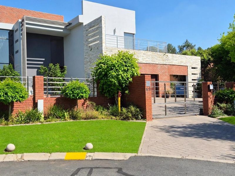 Modern double-story residence featuring a striking combination of brick and stone cladding, a paved driveway, and a secure gated entrance.