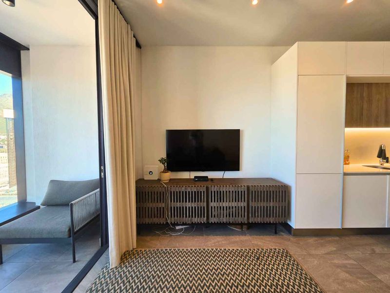 Modern open-plan living area featuring tiled floors, recessed lighting, and seamless access to a private balcony through large sliding glass doors.