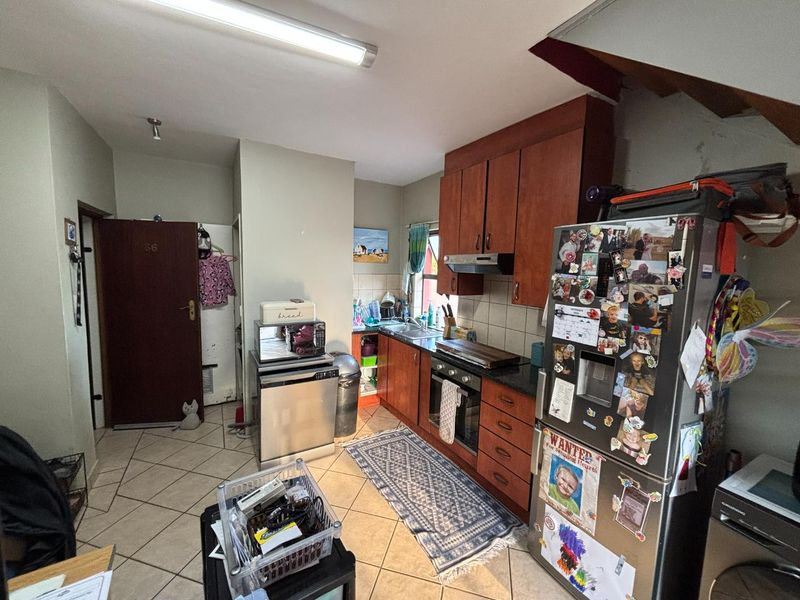 A functional kitchen featuring wooden cabinetry, built-in oven and hob, tiled backsplash, and tiled flooring, offering a practical layout for daily meal preparation.