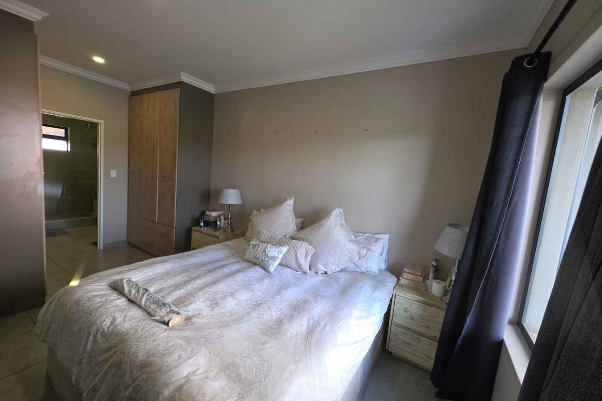 A well-maintained bedroom featuring built-in cupboards, tiled flooring, recessed lighting, and direct access to an en-suite bathroom.