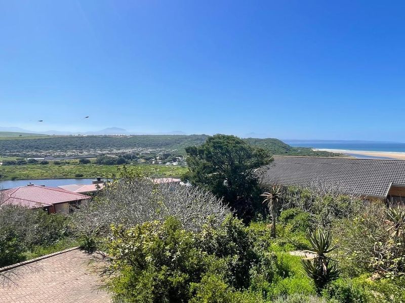 A scenic elevated view overlooking a coastal landscape, river, and surrounding residential properties, showcasing the natural beauty and location of the vacant land.