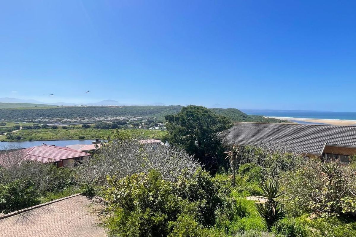 A scenic elevated view overlooking a coastal landscape, river, and surrounding residential properties, showcasing the natural beauty and location of the vacant land.