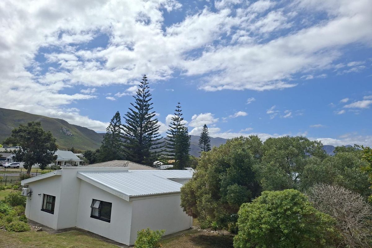 A view of the rear exterior of the property featuring a white building with a metal roof, set against a scenic mountain backdrop.