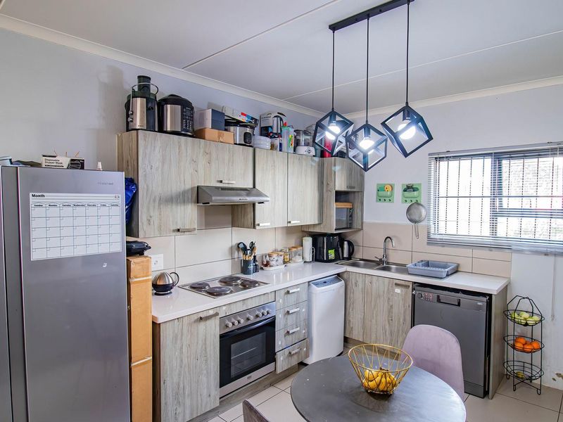 Functional kitchen featuring wood-look cabinetry, built-in oven and hob, tiled backsplash, and modern pendant lighting.