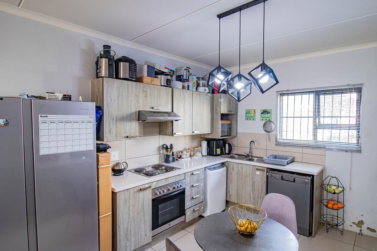Functional kitchen featuring wood-look cabinetry, built-in oven and hob, tiled backsplash, and modern pendant lighting.