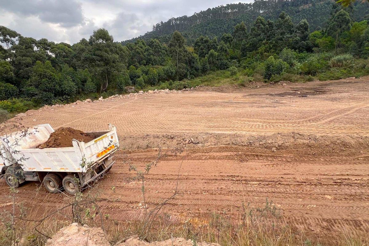 A view of a cleared commercial vacant land plot with earthworks in progress, featuring a natural hillside backdrop.