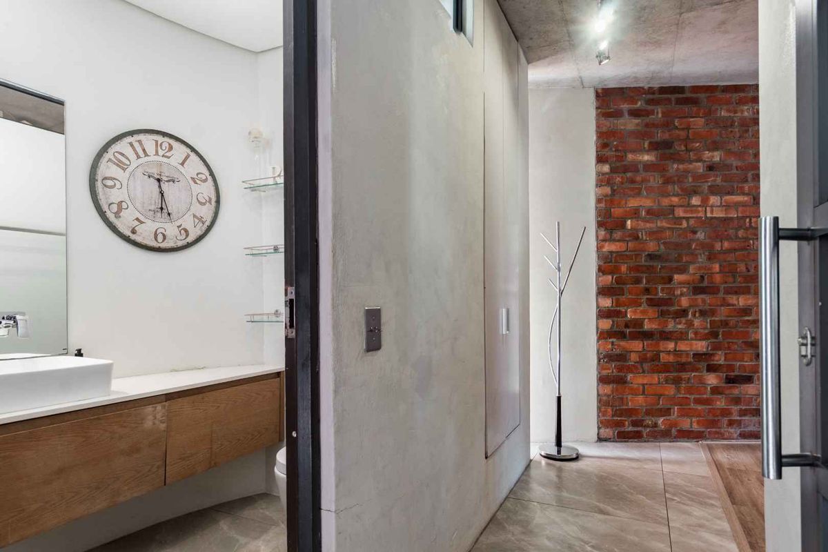 Modern bathroom featuring a floating vanity with vessel sink, complemented by an industrial-style exposed brick wall and concrete ceiling finishes.