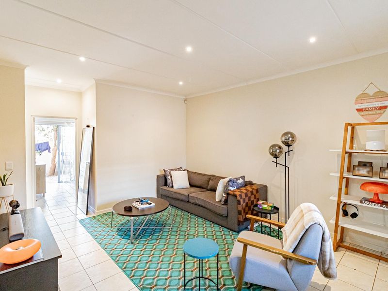 A bright and well-maintained living room featuring neutral walls, tiled flooring, and recessed downlighting, providing a comfortable and functional living space.