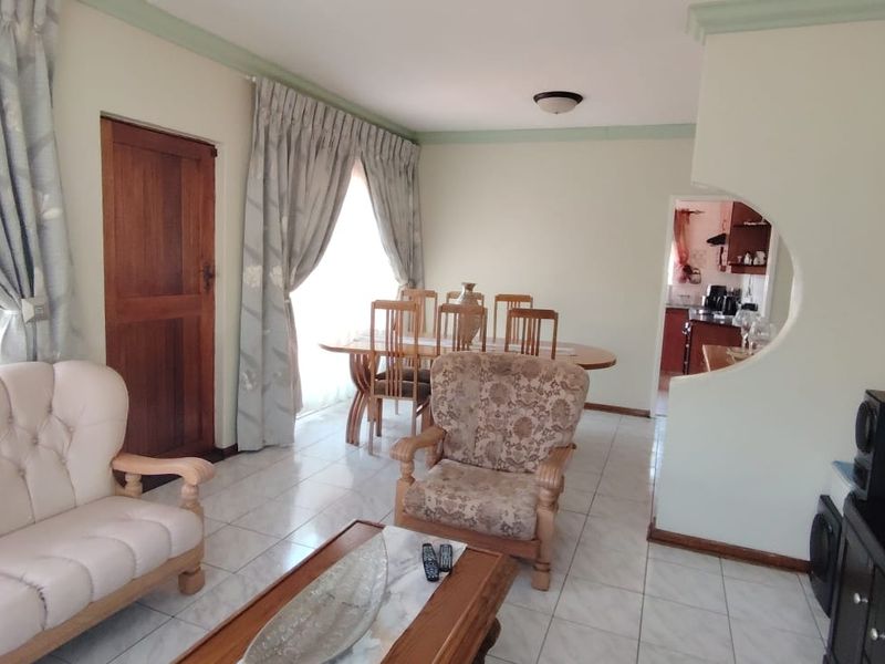 Open plan living and dining area featuring tiled flooring, a decorative archway, and direct access to the kitchen area.