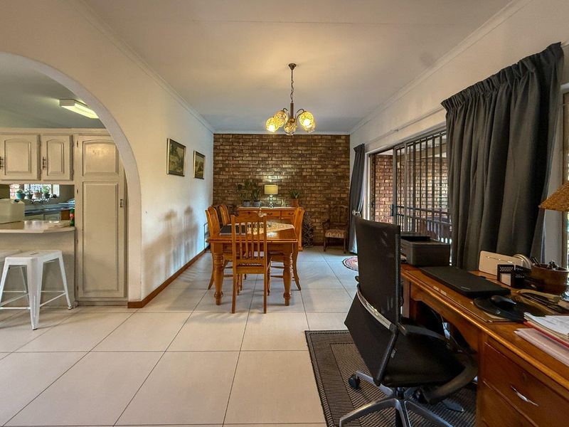 Open-plan living and dining area featuring a striking exposed brick wall, tiled flooring, and sliding doors leading to an outdoor space.