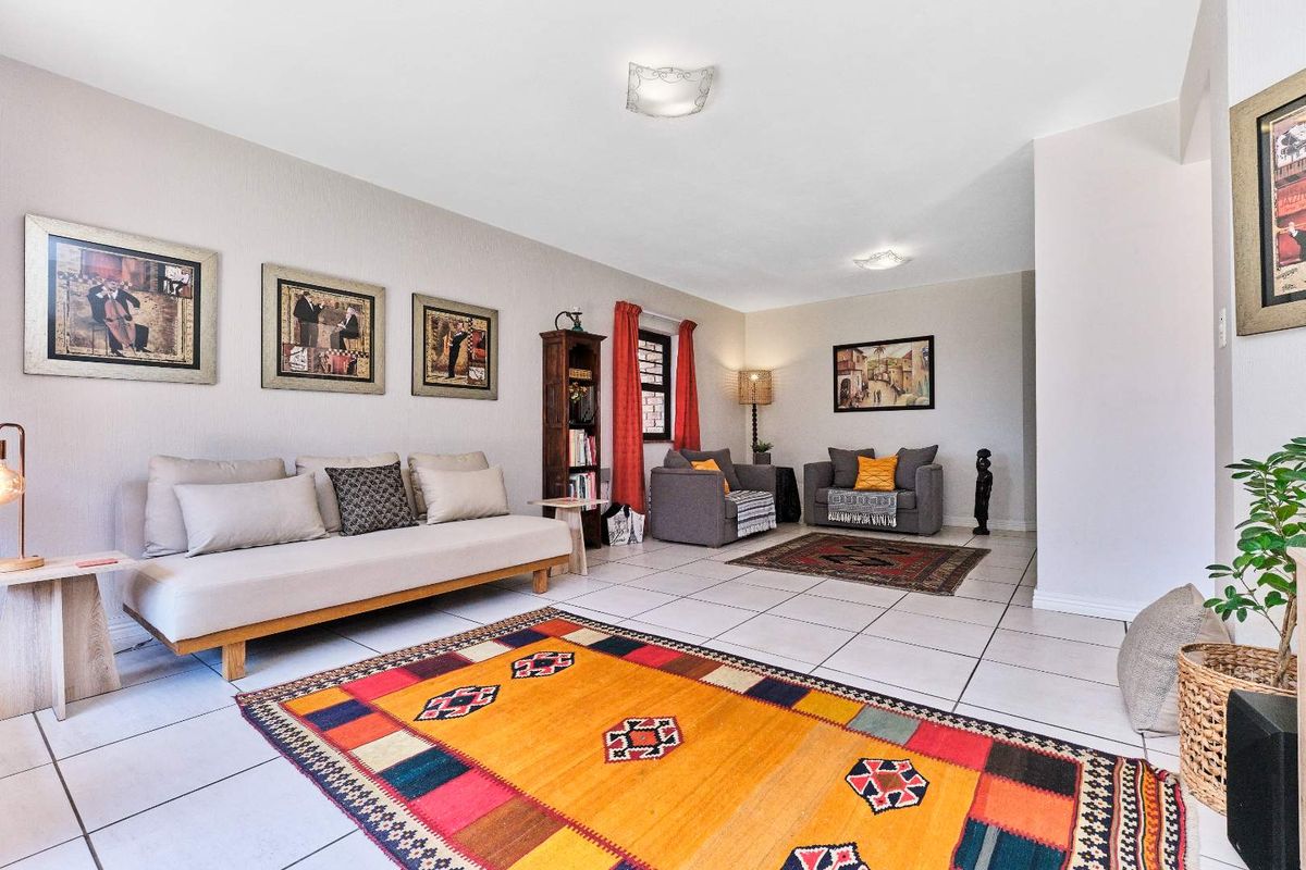 A spacious living room featuring neutral tiled flooring and flush-mounted ceiling lighting, offering a versatile open-plan layout suitable for comfortable family living.