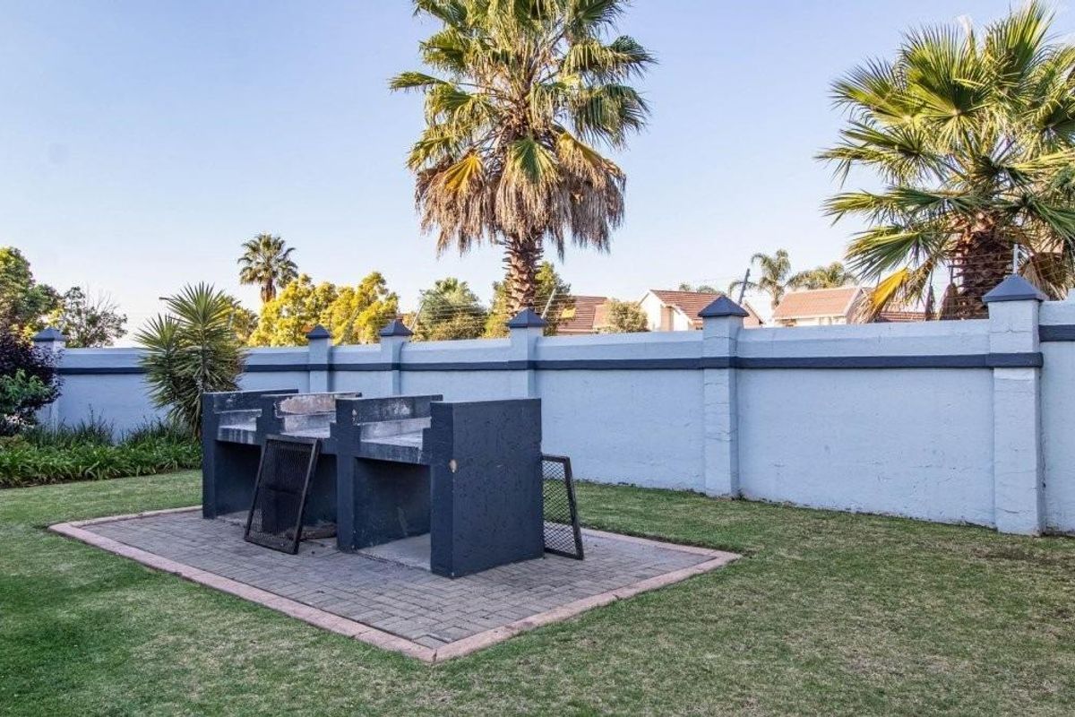 A private garden area featuring a built-in braai, paved patio section, and a secure perimeter wall.