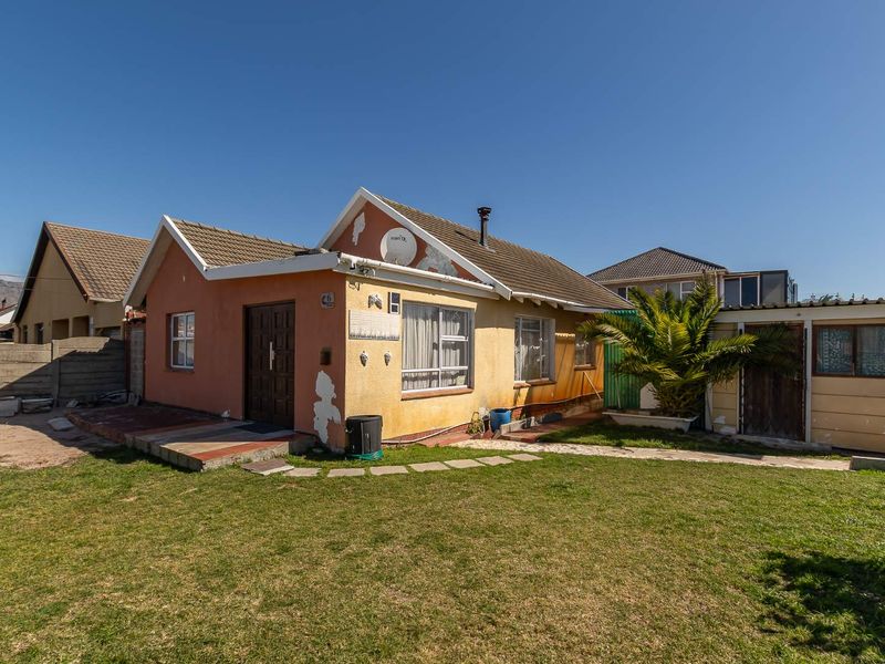 Front view of a detached house featuring a tiled roof, chimney, and a front garden area with a concrete pathway.