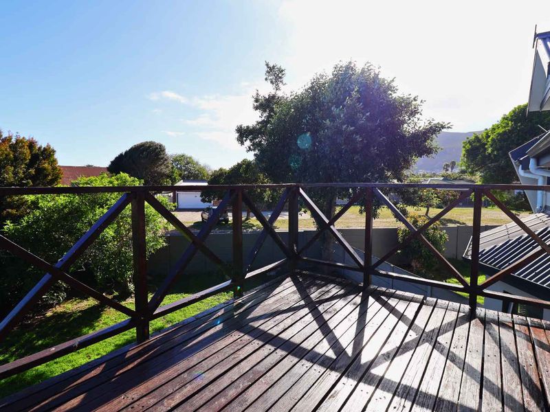 An elevated timber balcony featuring a wooden balustrade, overlooking the garden and surrounding neighborhood.