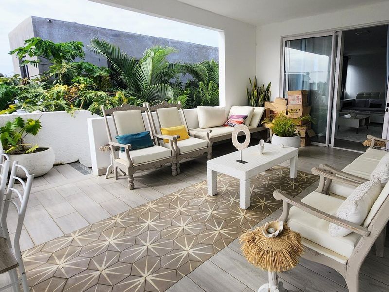 A spacious covered patio featuring tiled flooring and large sliding glass doors, providing a seamless transition to the outdoor living area.