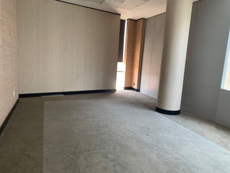 An empty office space featuring a structural column, neutral wall finishes, and carpeted flooring, offering a blank canvas for professional workspace configuration.