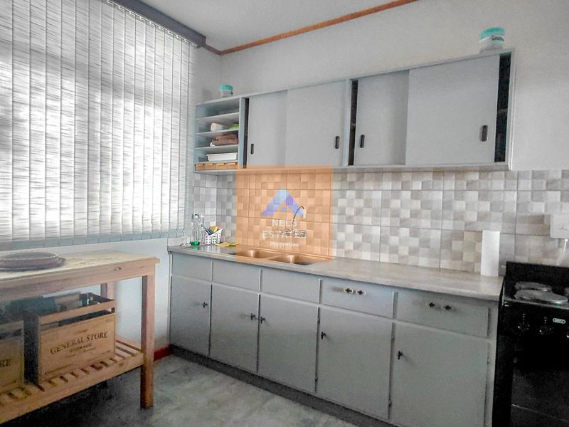 A functional kitchen featuring built-in cabinetry, a double basin sink, tiled backsplash, and a freestanding stove, offering a practical layout for daily use.