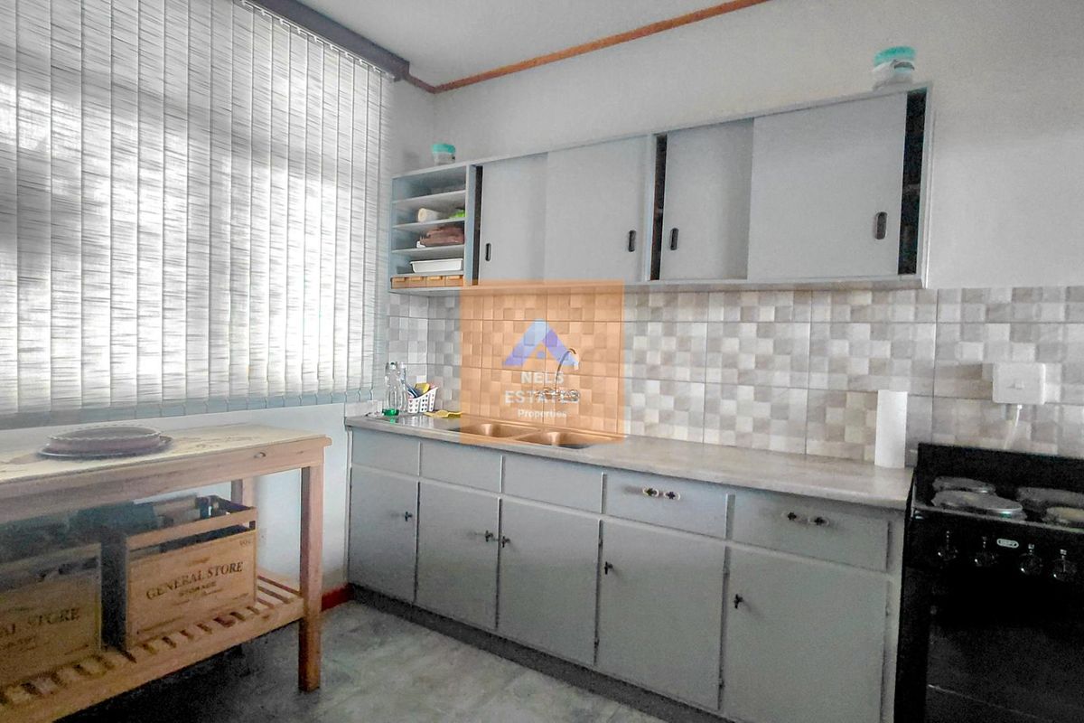 A functional kitchen featuring built-in cabinetry, a double basin sink, tiled backsplash, and a freestanding stove, offering a practical layout for daily use.