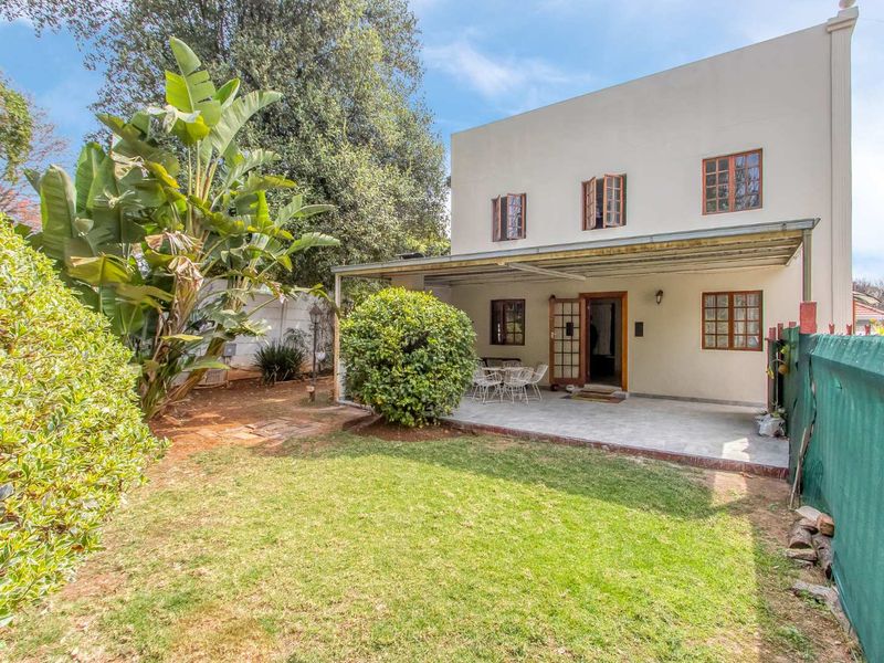 Rear view of the property featuring a covered patio area, established garden, and lawn space with direct access to the home.