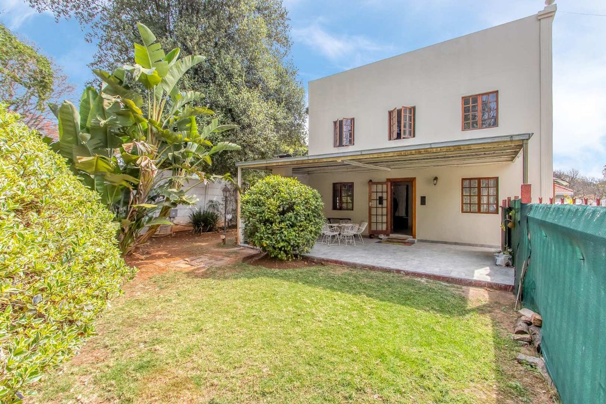 Rear view of the property featuring a covered patio area, established garden, and lawn space with direct access to the home.