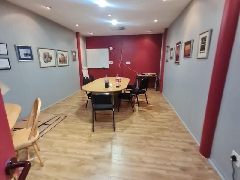 A functional office space featuring laminate flooring, recessed ceiling lighting, and air conditioning, suitable for a meeting room or collaborative workspace.