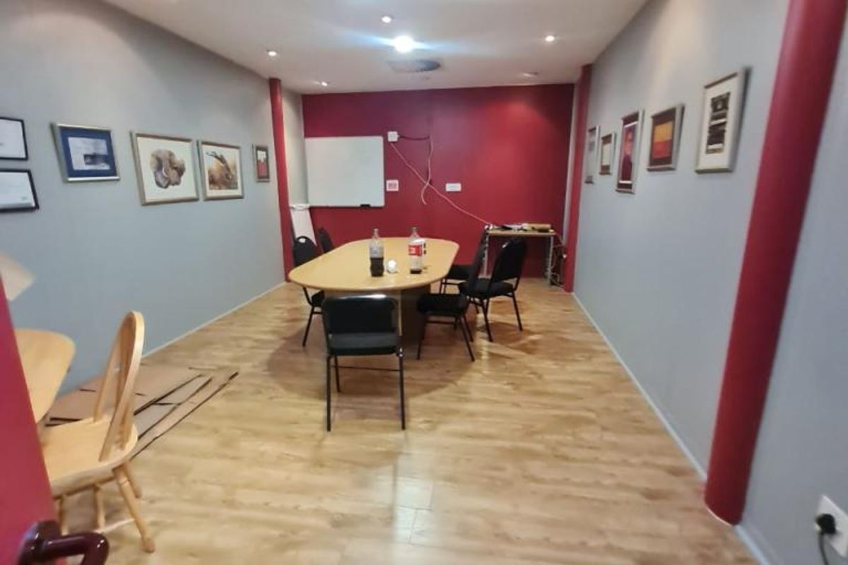 A functional office space featuring laminate flooring, recessed ceiling lighting, and air conditioning, suitable for a meeting room or collaborative workspace.