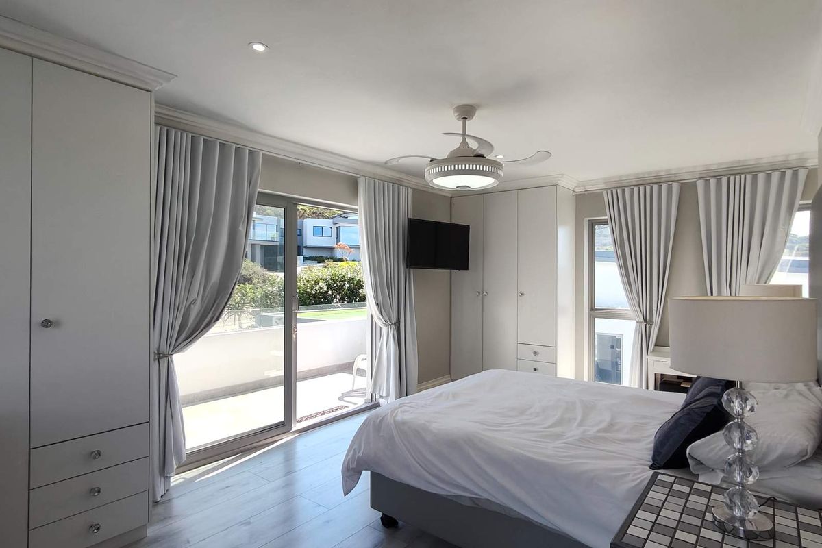 A well-maintained bedroom featuring built-in cupboards, a ceiling fan, and a sliding glass door providing access to an outdoor balcony area.