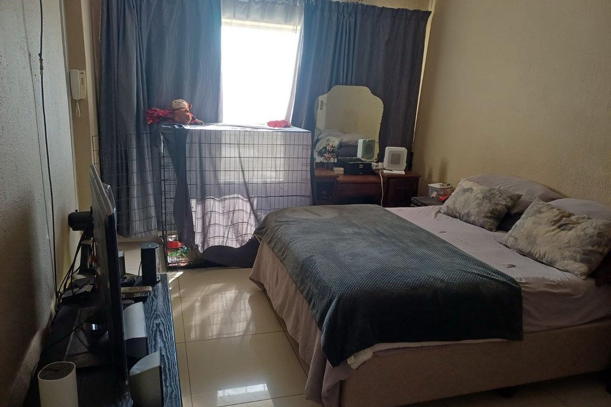 A standard bedroom featuring tiled flooring and large windows with curtain rails, providing a functional space for rest.