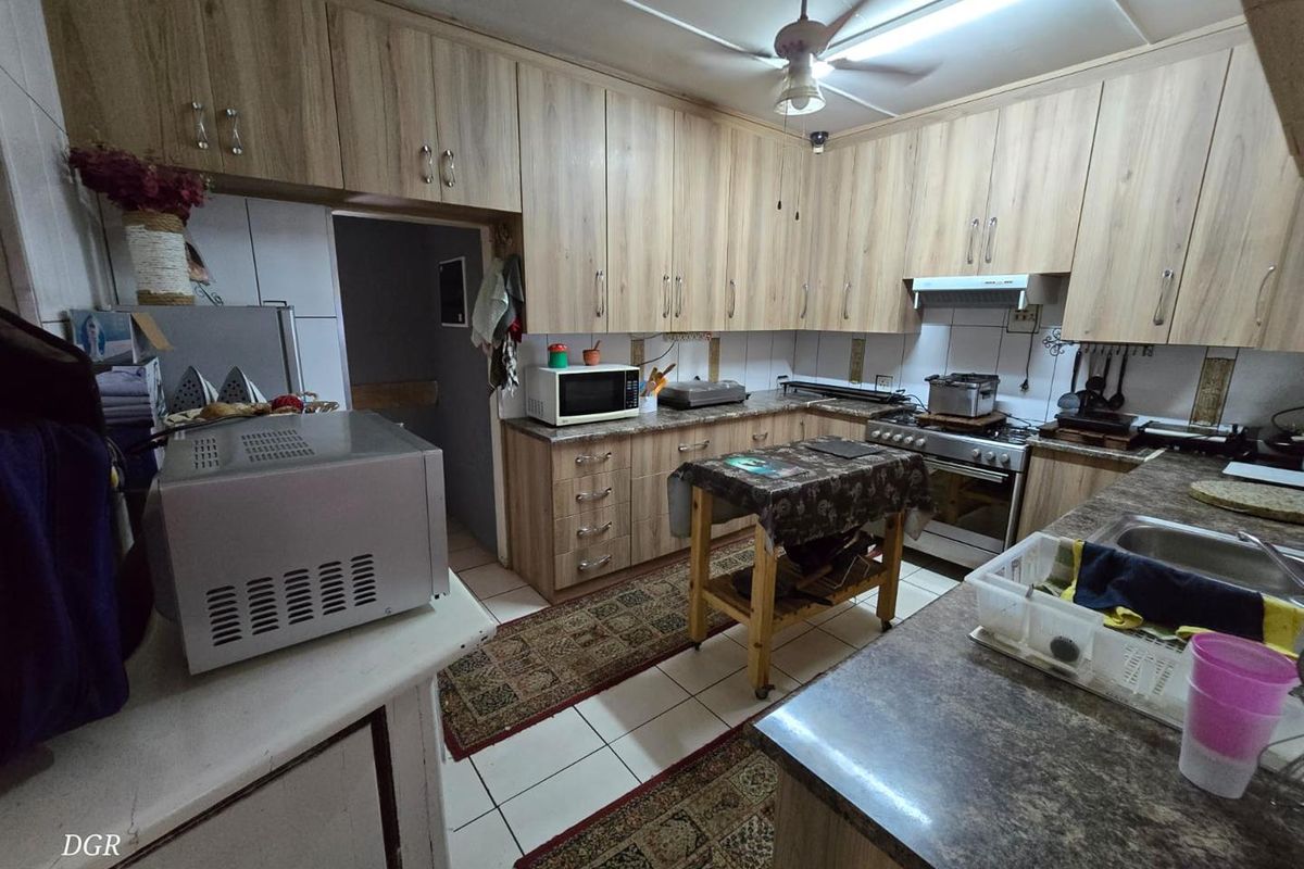 A functional kitchen featuring wood-look cabinetry, tiled flooring, a built-in oven with extractor fan, and ample counter space for meal preparation.
