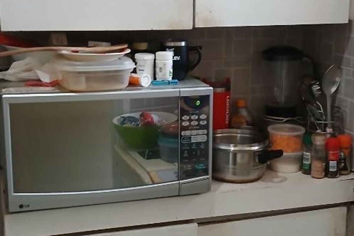 A compact kitchen area featuring white built-in cabinetry, a tiled backsplash, and tiled flooring, showing signs of wear and tear.