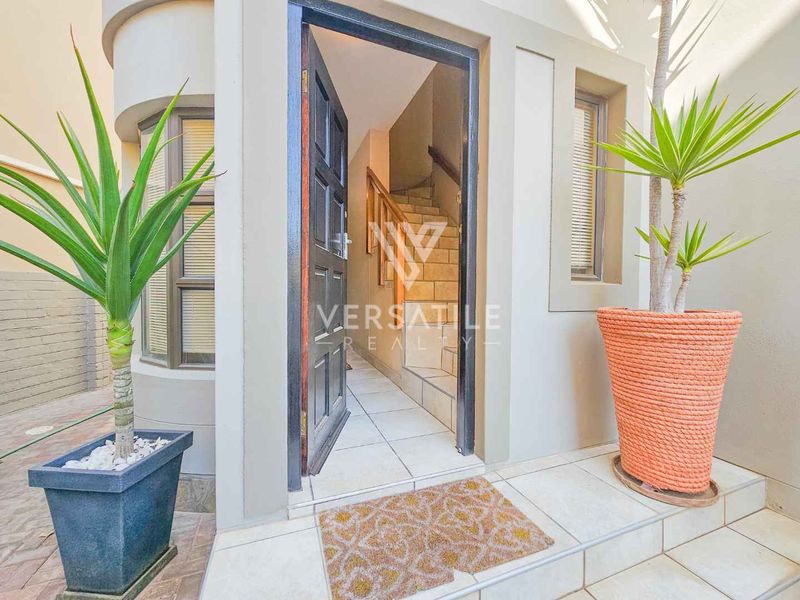A welcoming entrance featuring a timber front door, tiled porch area, and an internal staircase with a wooden handrail.
