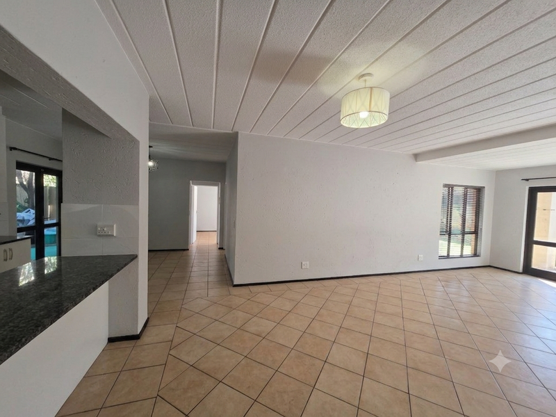 Spacious open-plan living area featuring tiled flooring, textured ceilings, and a granite breakfast bar, offering a bright and versatile layout.