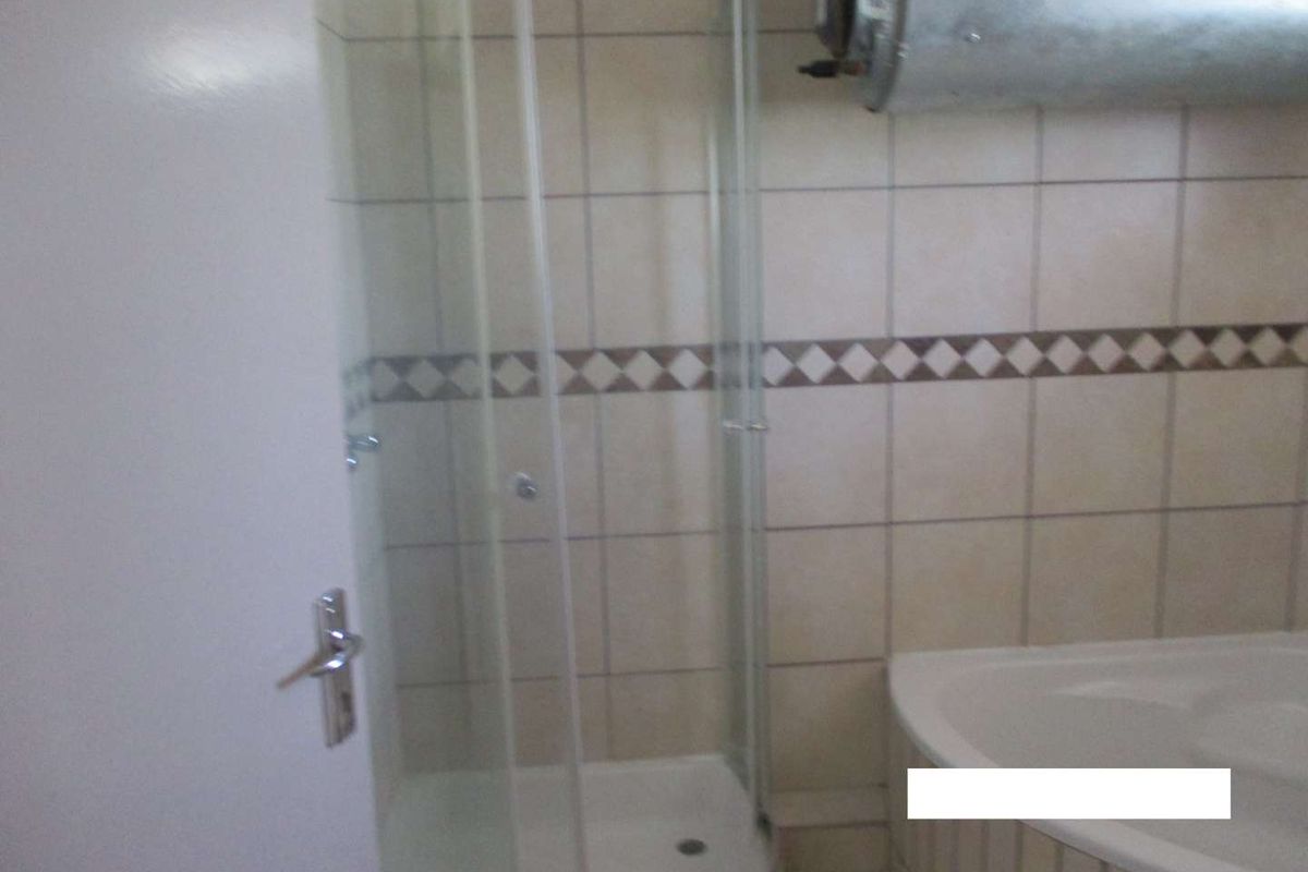 Bathroom featuring a corner shower enclosure, bathtub, and wall-mounted water heater with tiled finishes.